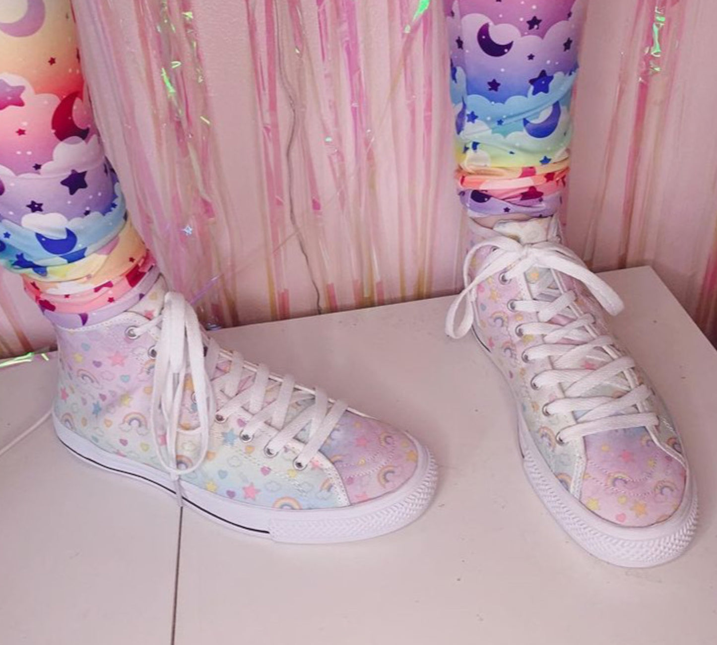 Close-up of cute pastel-colored shoes with decorative elements, displayed on a pink background