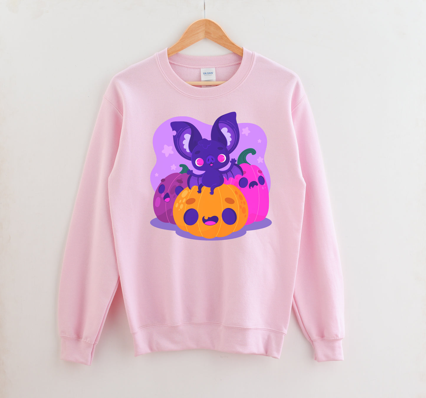 Pink sweatshirt with a colorful graphic of a bat and pumpkins on a white background