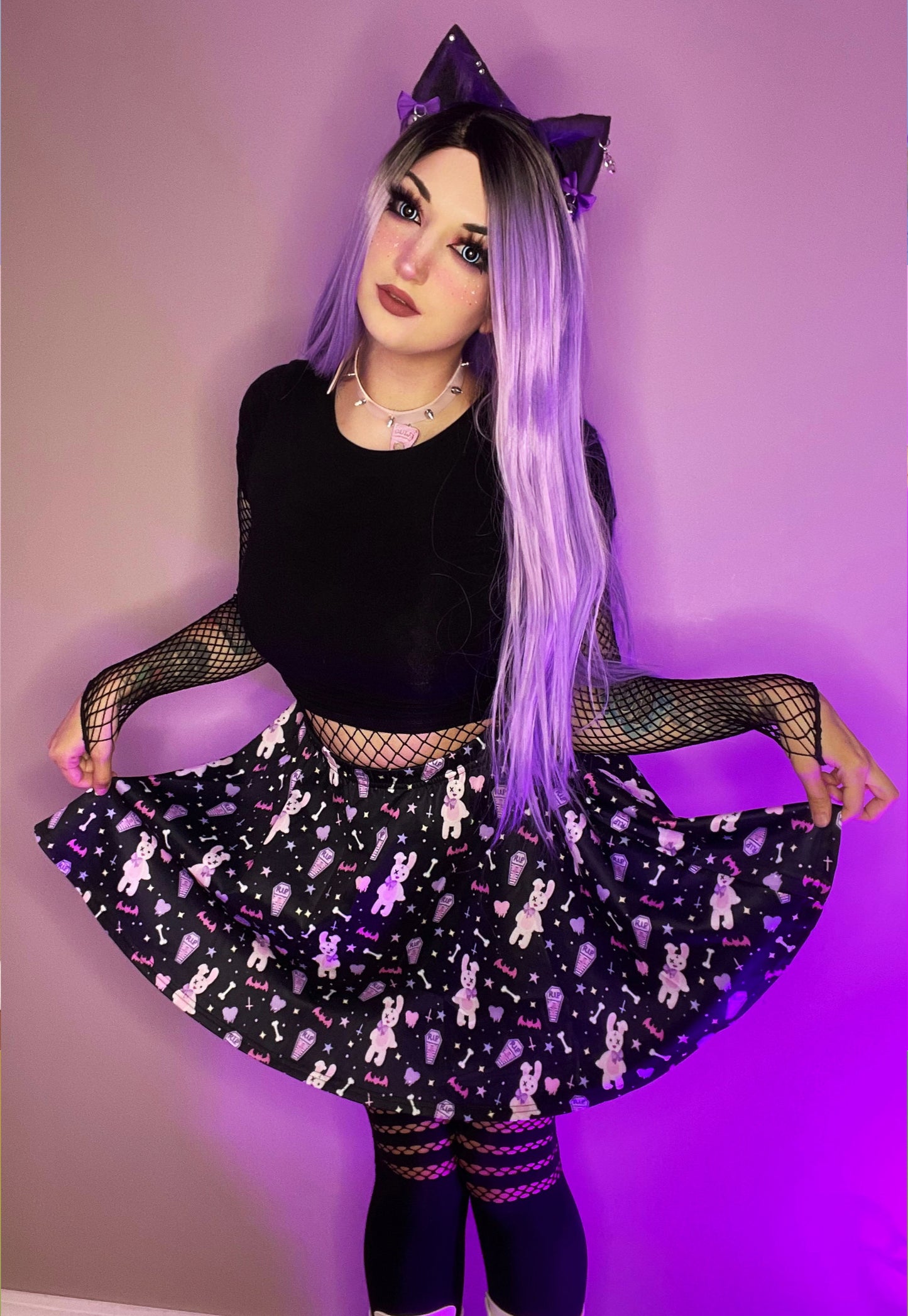 Young girl wearing a pastel goth skater skirt with creepy cute coffin skull and bunny design.