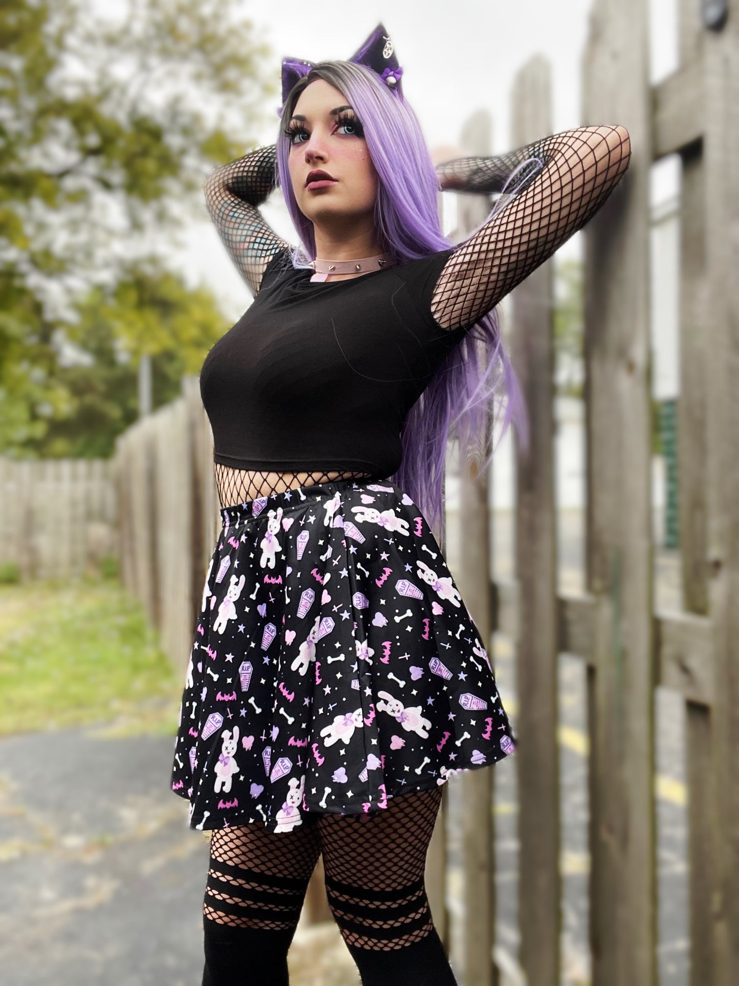 Young girl wearing a pastel goth skater skirt with creepy cute coffin skull and bunny design.