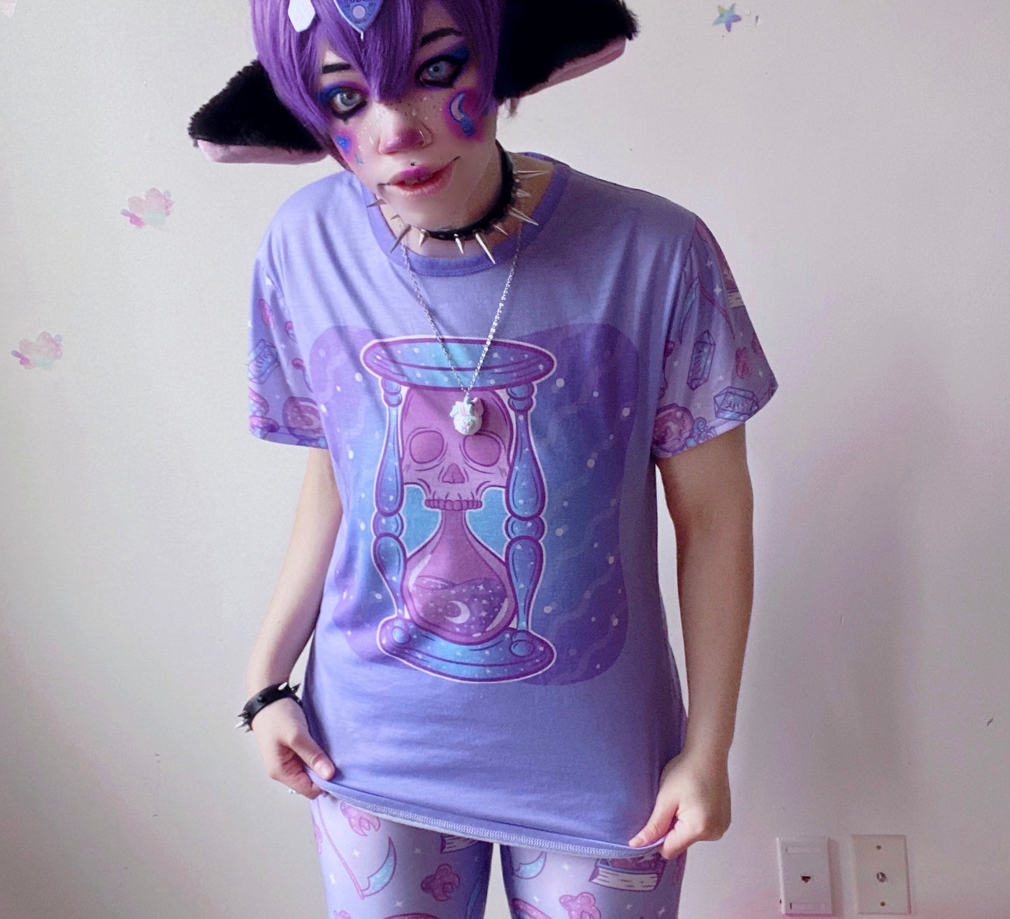 model wearing a pastel goth t-shirt with soft colours and spooky skull hourglass design.