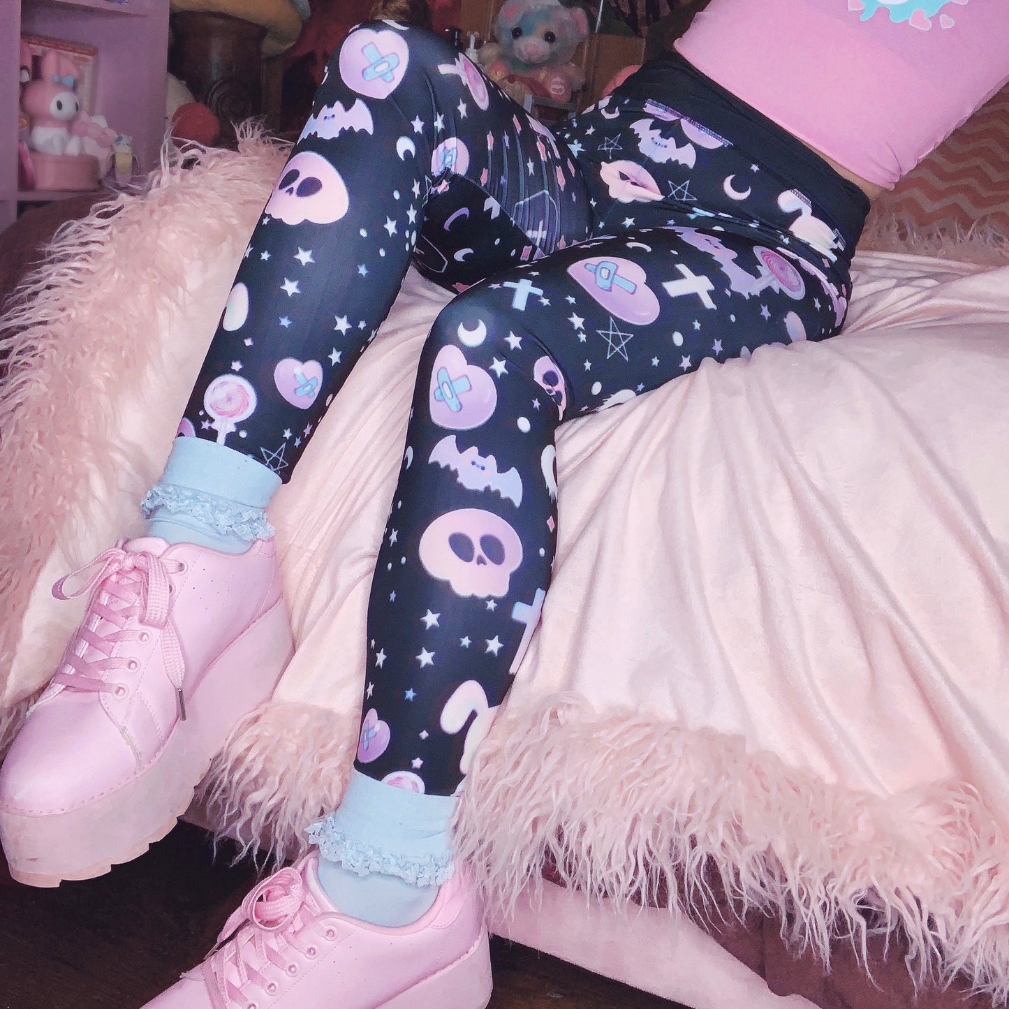 Young girl wearing a pastel goth leggings with creepy skull and bat design.