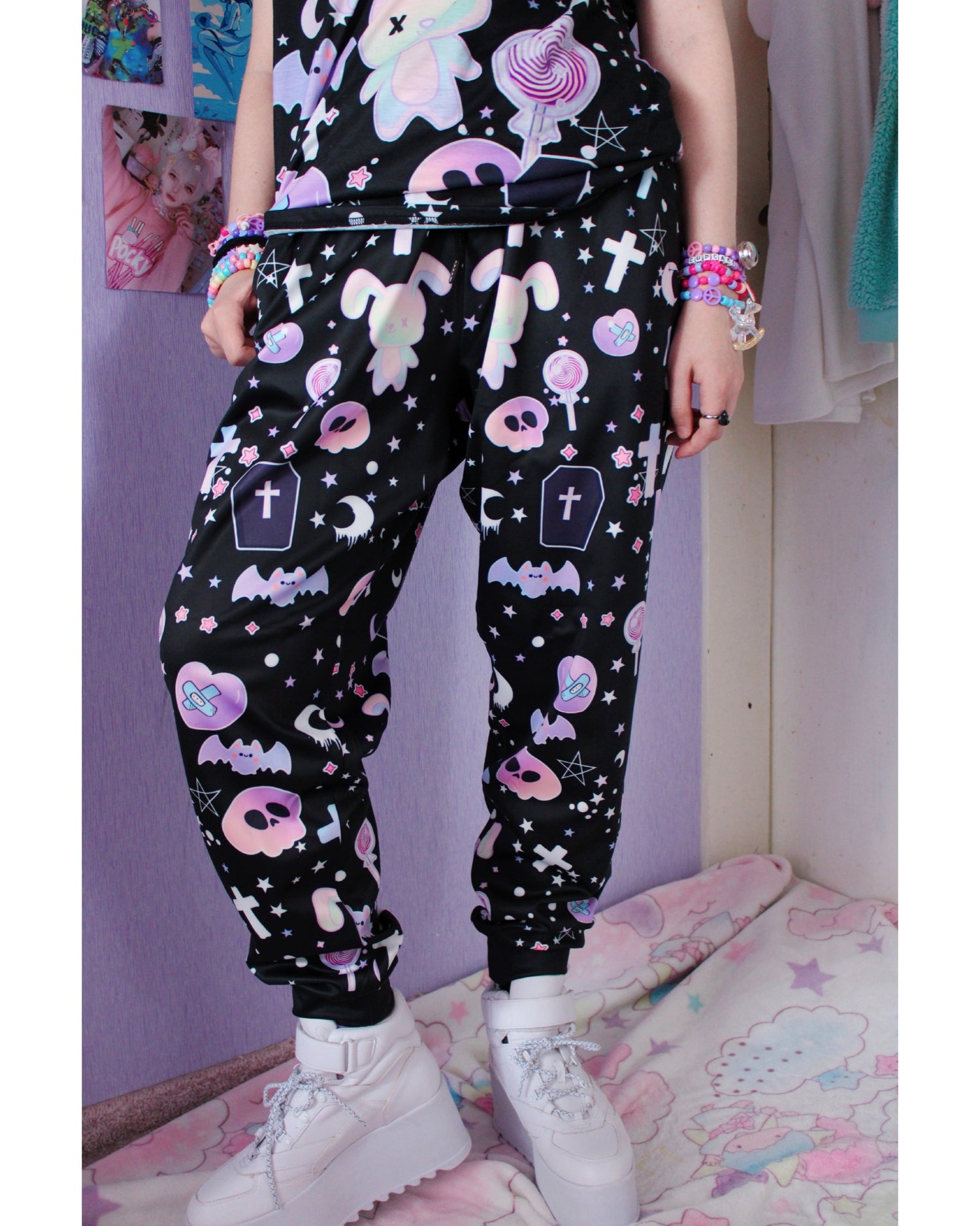 Model wearing a pastel goth joggers with black and purple colours and creepy cute bats and skulls design