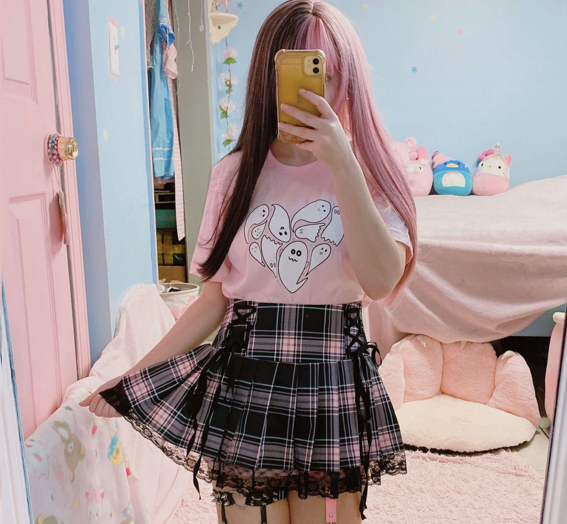 Girl wearing a cute Halloween t-shirt with pink hair taking a mirror selfie in a room with colorful decor.