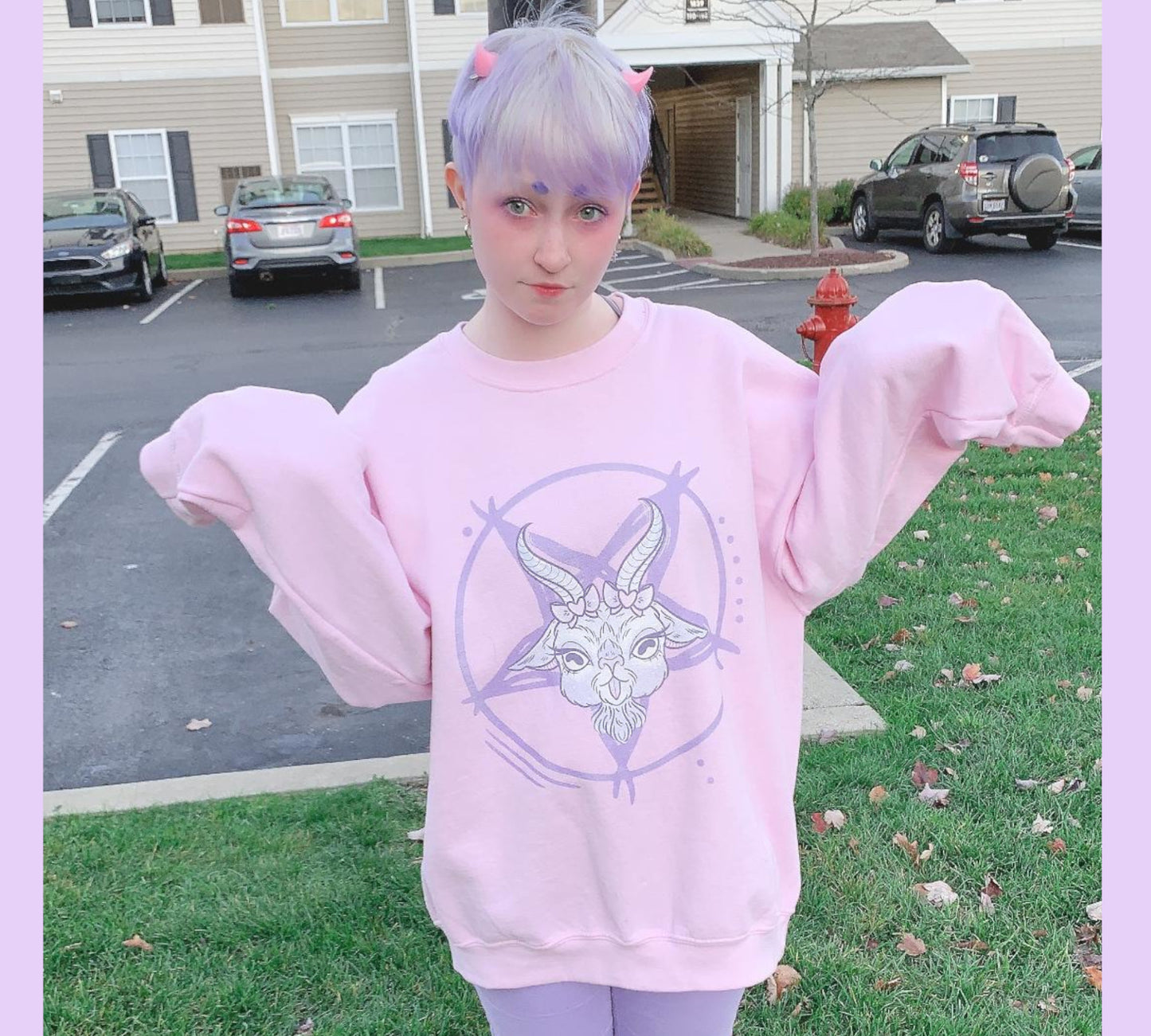 Young girl wearing a pastel goth sweatshirt with soft colors and creepy cute goat design