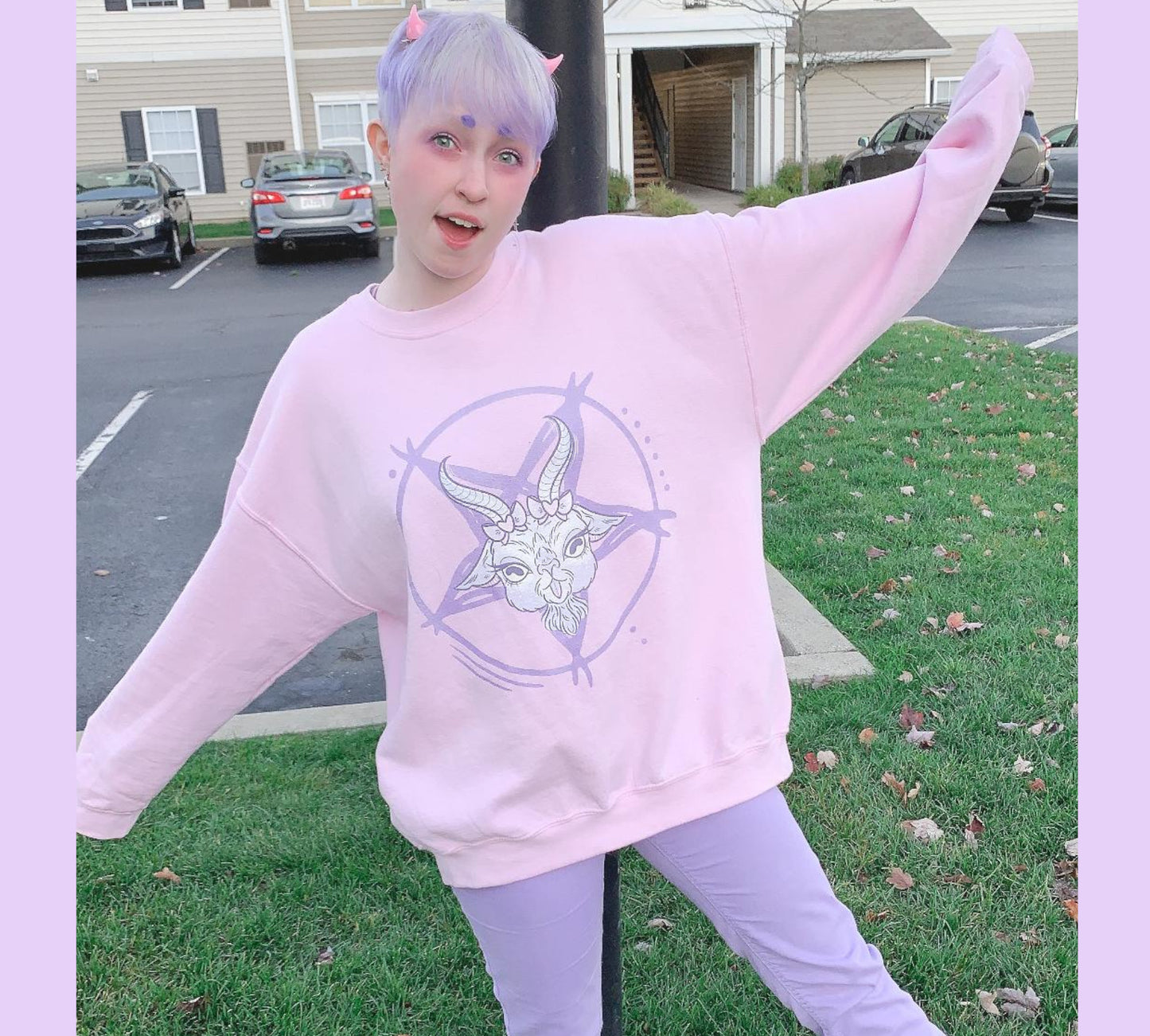 Young girl wearing a pastel goth sweatshirt with soft colors and creepy cute goat design