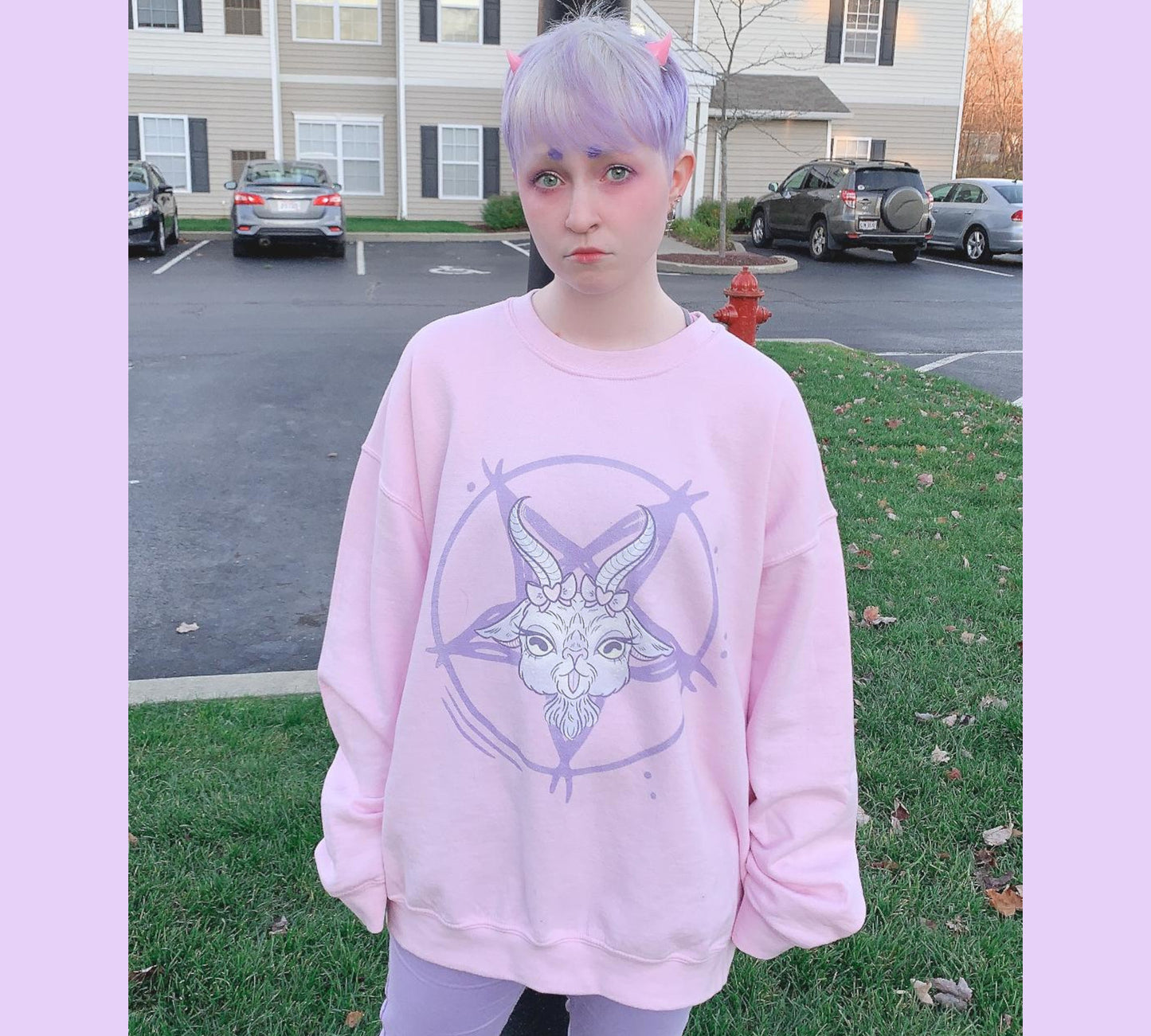 Young girl wearing a pastel goth sweatshirt with soft colors and creepy cute goat design