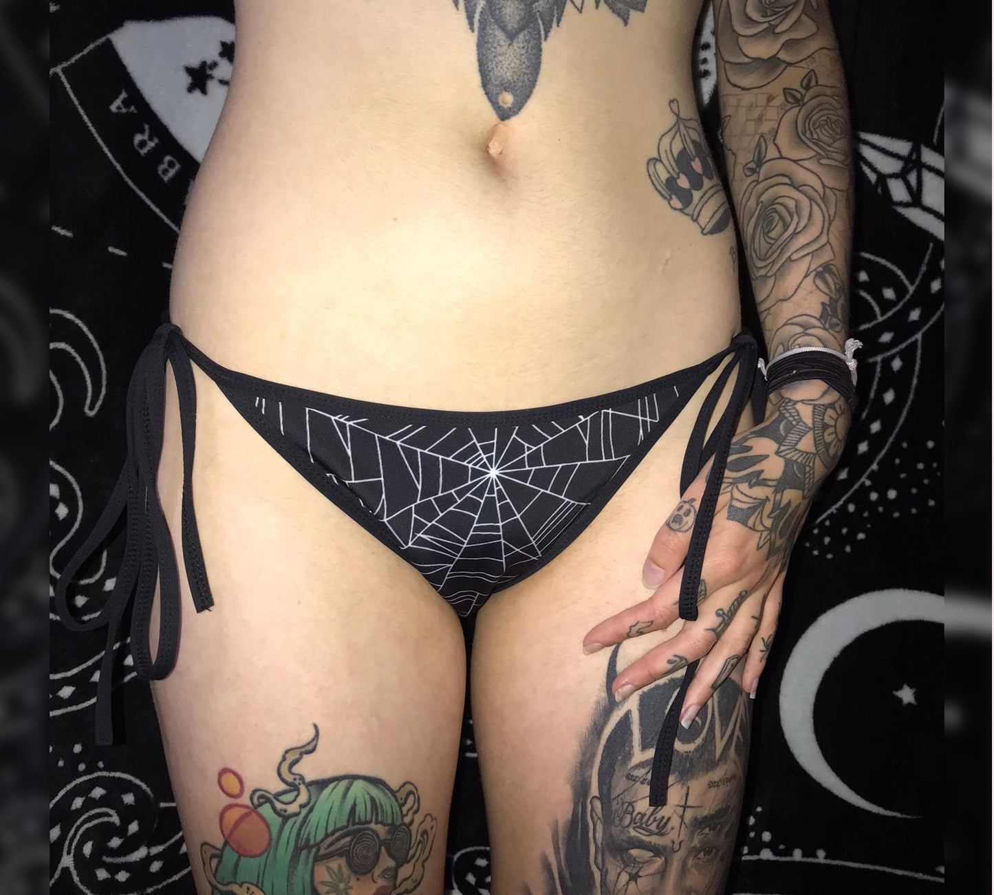 Girl modelling a black and white goth bikini with spiderweb designs