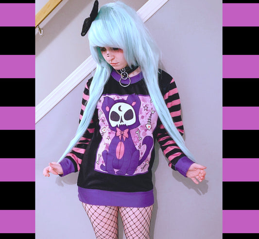 Young girl wearing a pastel goth sweatshirt with cute cat  design.