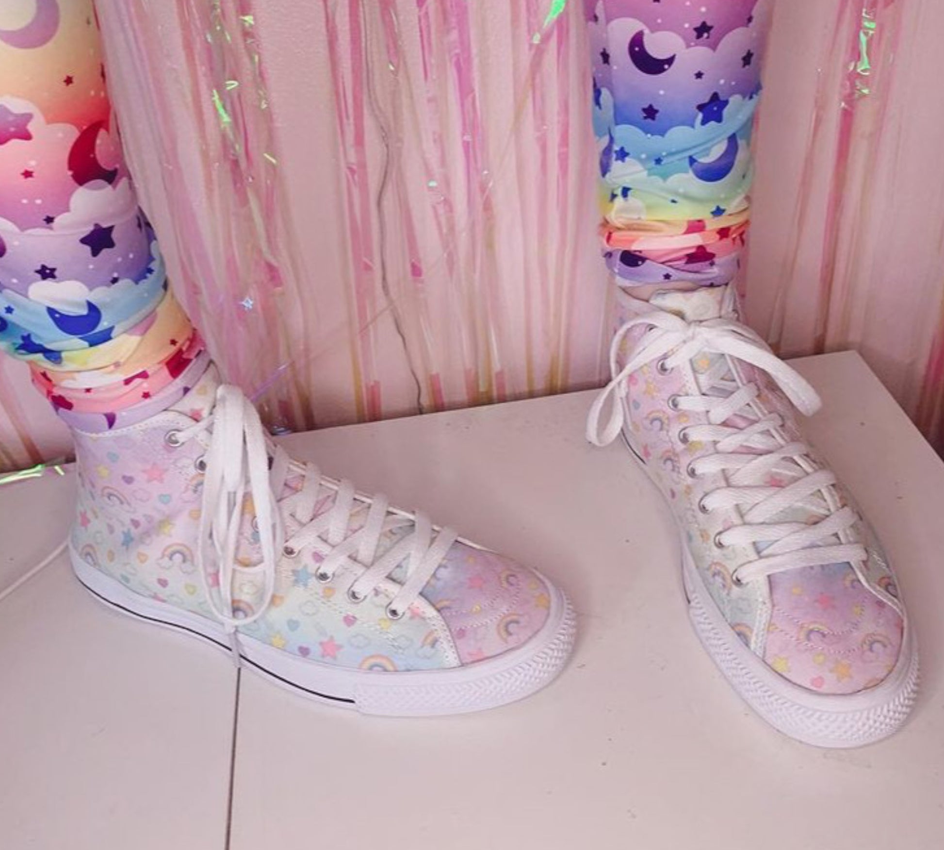 Close-up of cute pastel-colored shoes with decorative elements, displayed on a pink background