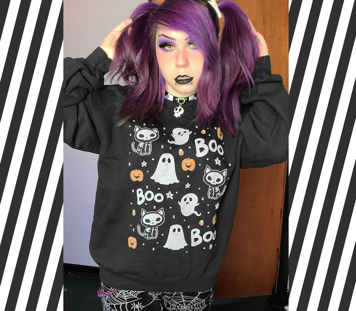 Person wearing a black sweatshirt with Halloween-themed designs in a room.