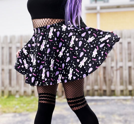 Young girl wearing a pastel goth skater skirt with creepy cute coffin skull and bunny design.