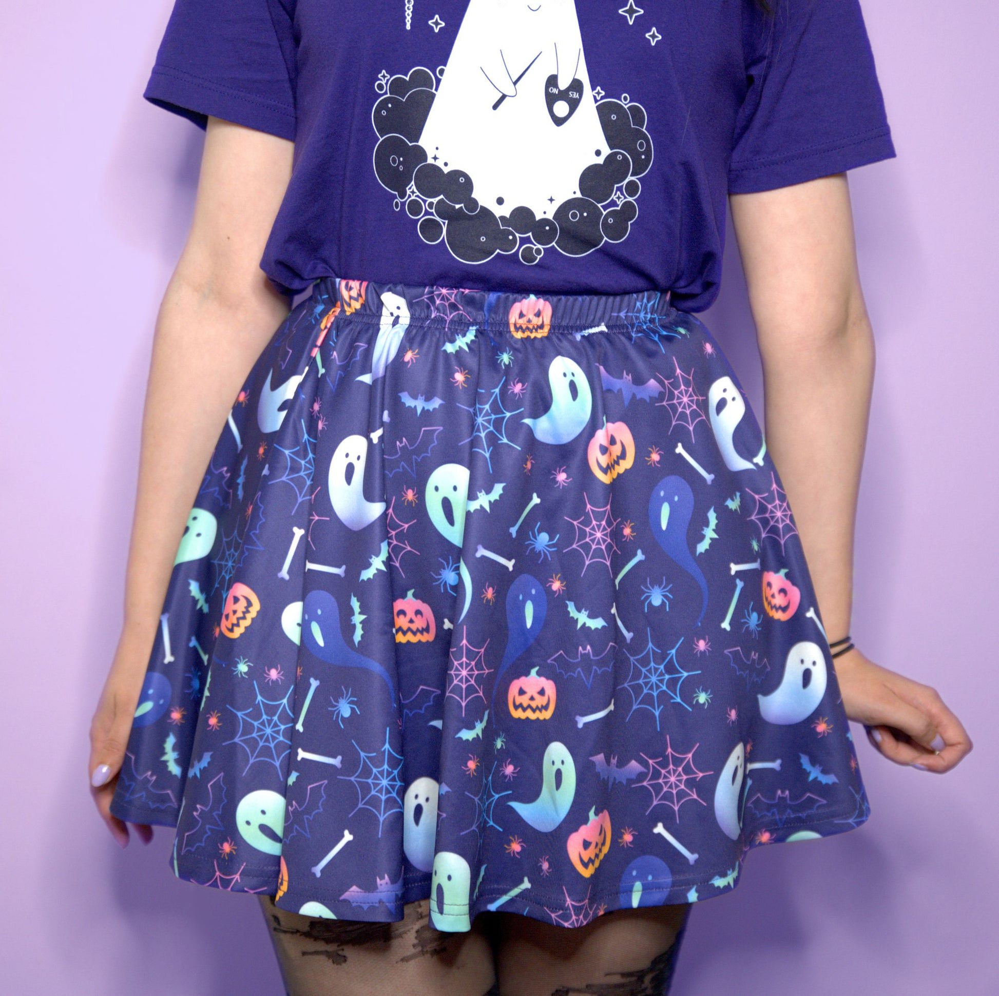 Young girl wearing a pastel goth Halloween skirt with pumpkin ghosts desing.