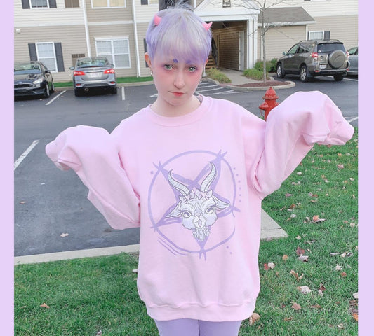 Young girl wearing a pastel goth sweatshirt with soft colors and creepy cute goat design