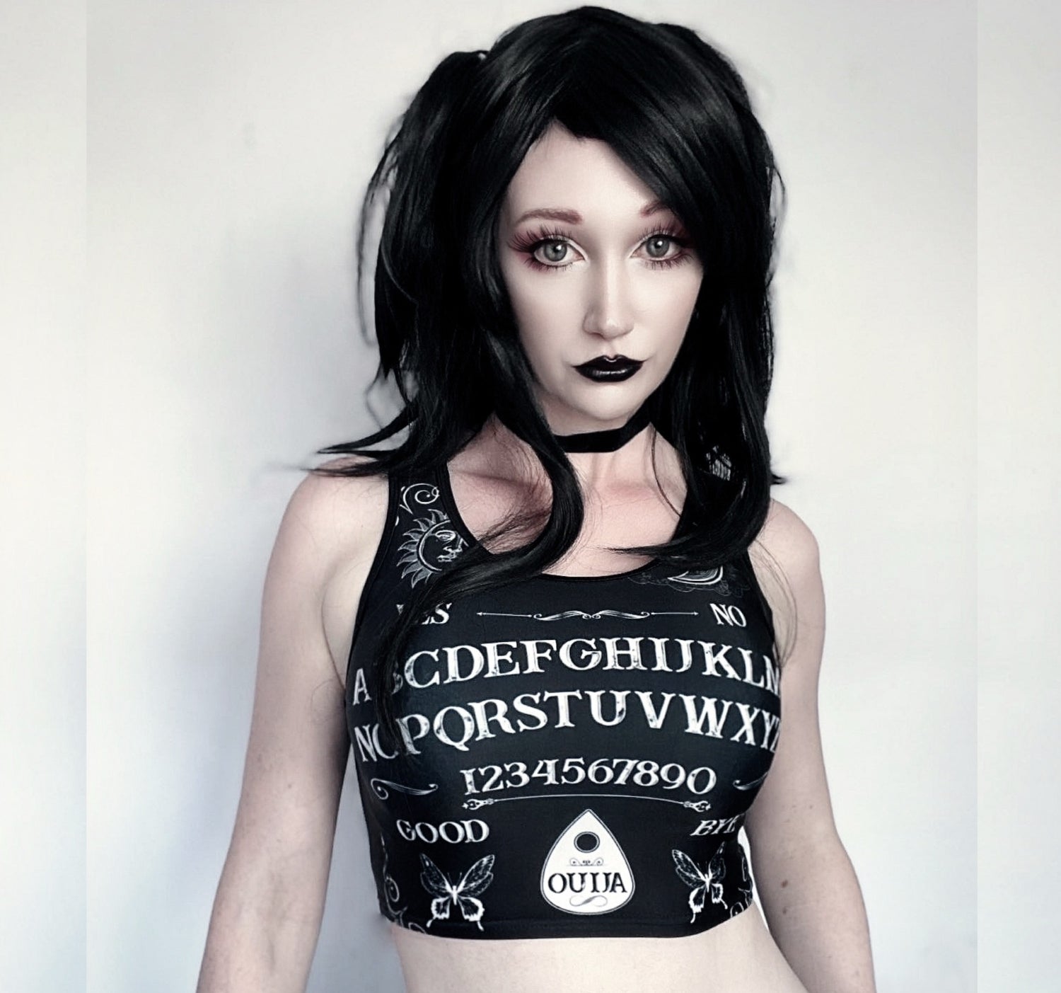 Girl modeling a goth crop top  with Ouija board design