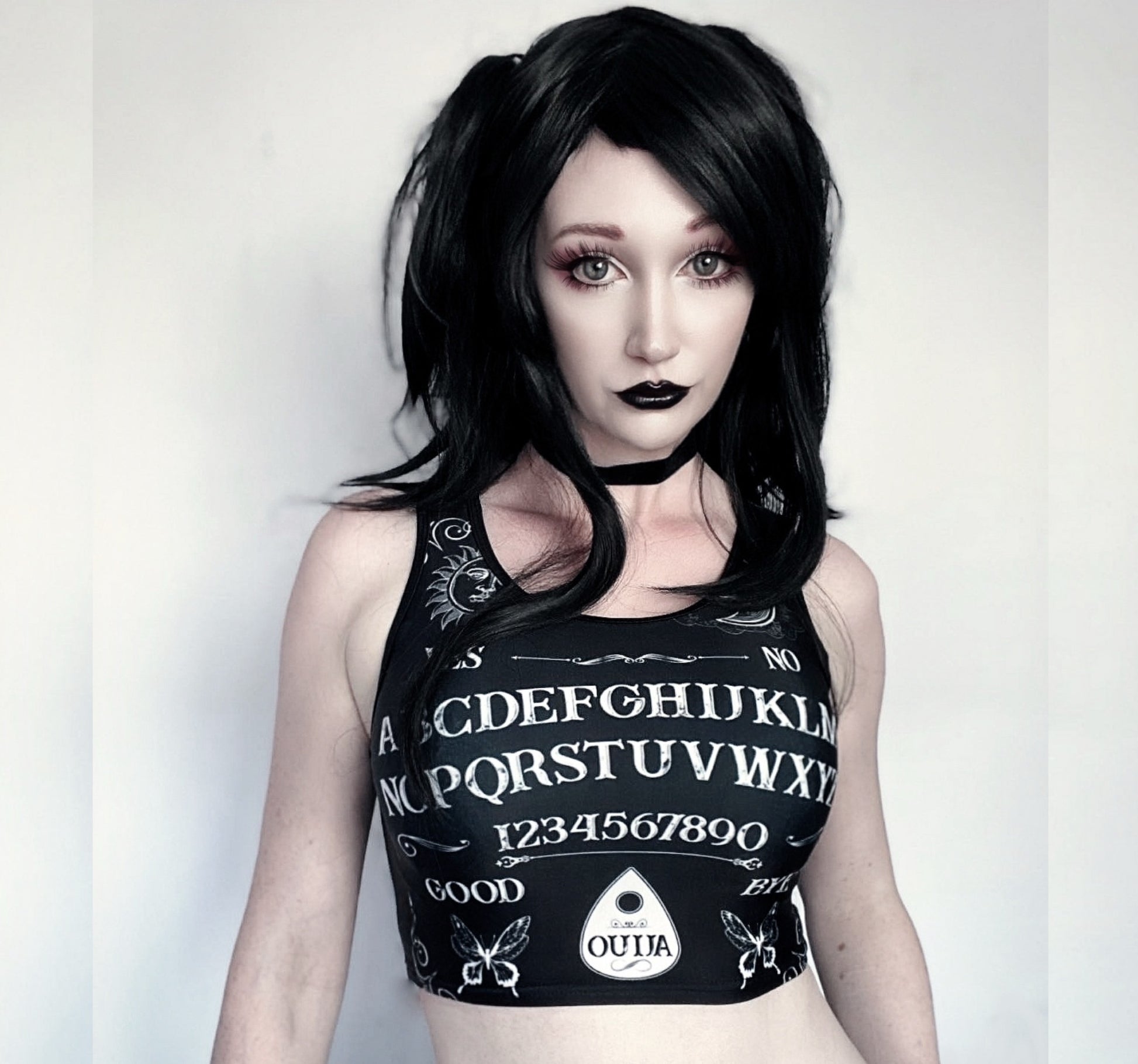 Girl modeling a goth crop top  with Ouija board design