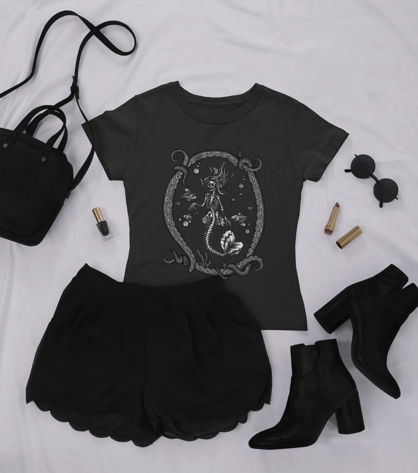 goth t-shirt with skeleton mermaid print and black skirt and boots  on white background.