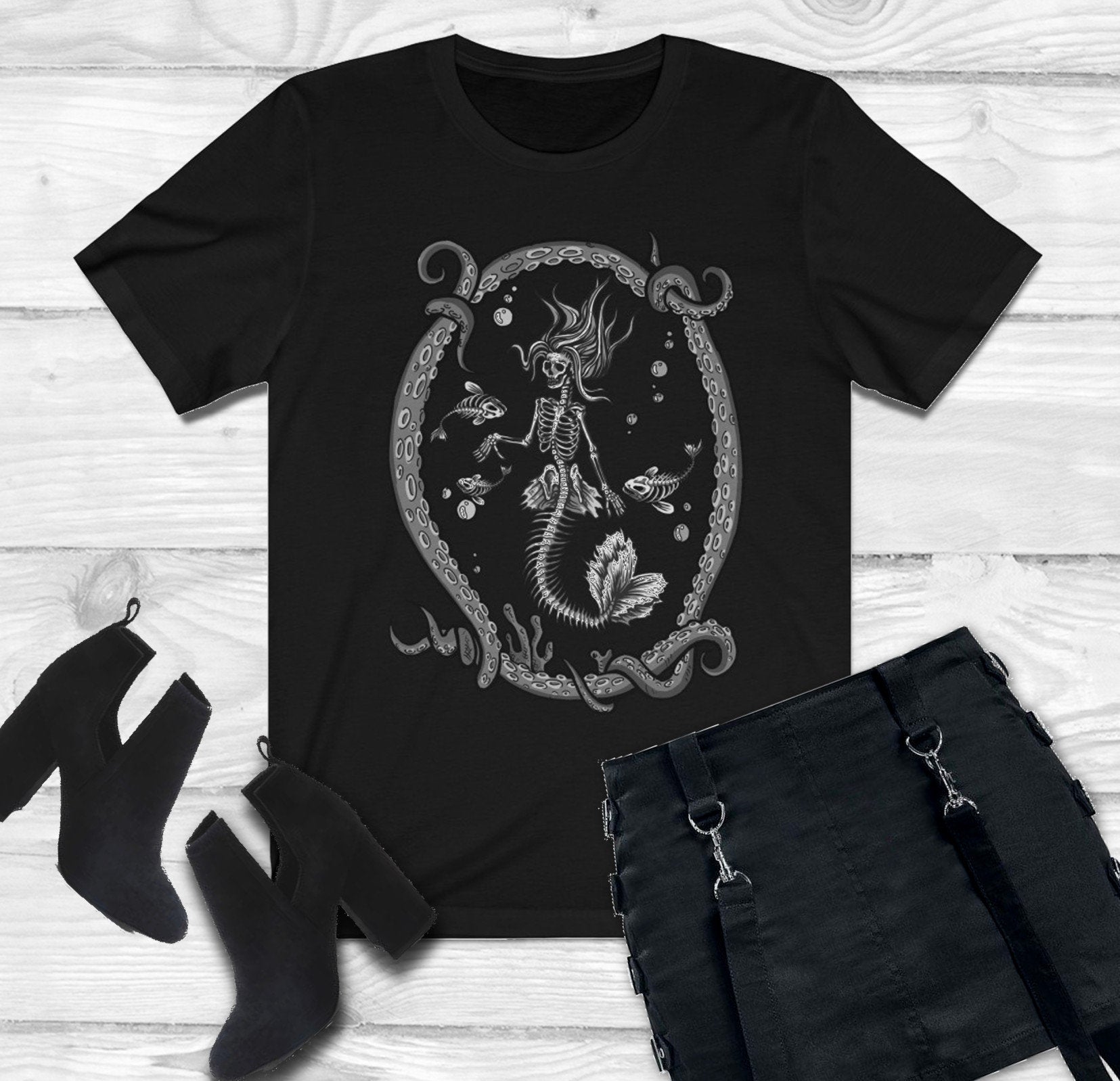 goth t-shirt with skeleton mermaid print and black skirt and boots  on white background.